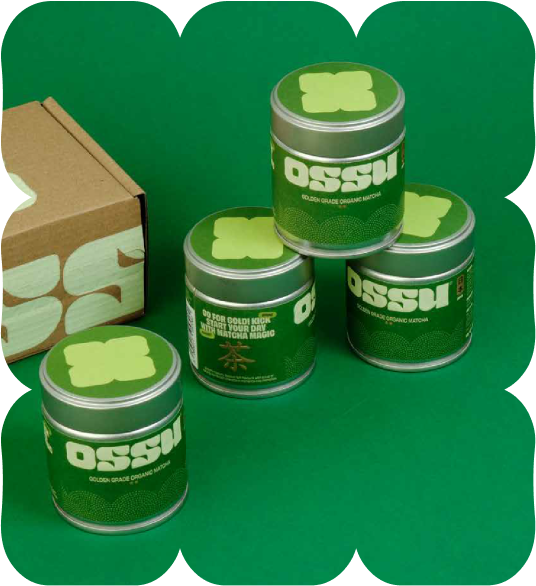 Stacked OSSU Golden Grade organic matcha tins beside branded cardboard box on green background