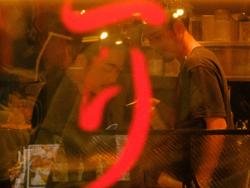 Chefs working inside a warmly lit Japanese restaurant kitchen at night