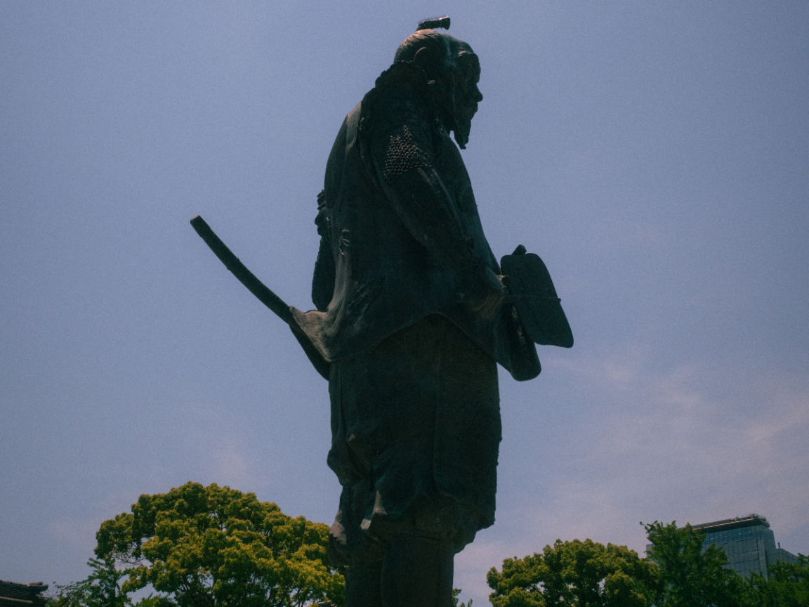 Statue of a traditional Japanese warrior viewed from below against the sky