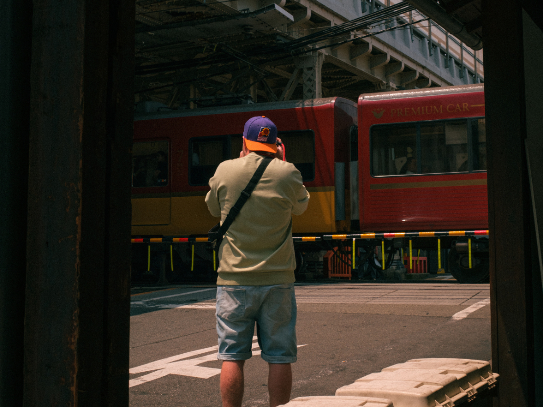 Man photographing a passing train at a railway crossing