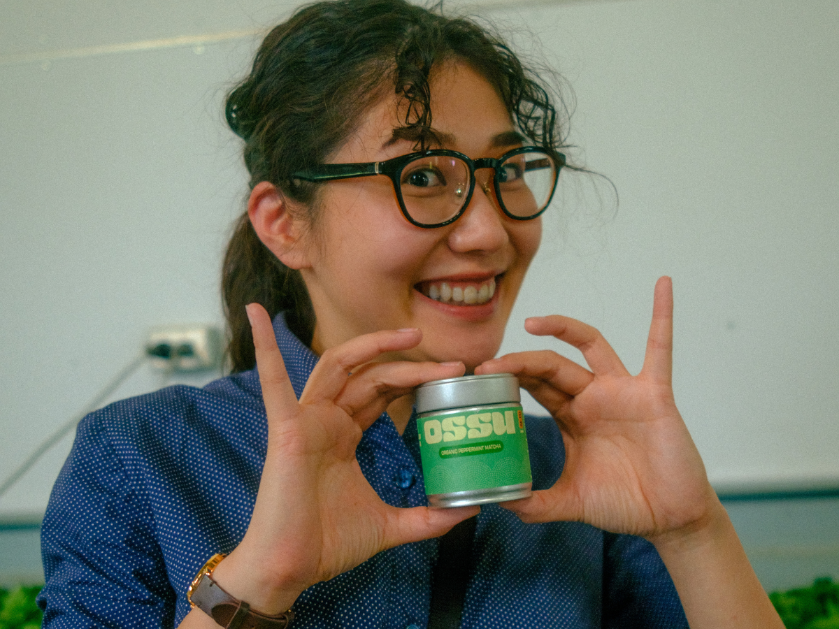 Smiling woman holding an OSSU matcha tin in her hands