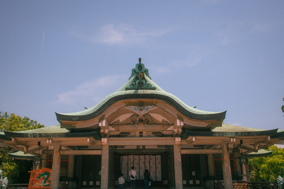 Traditional Japanese temple building with ornate curved roof under a clear blue sky