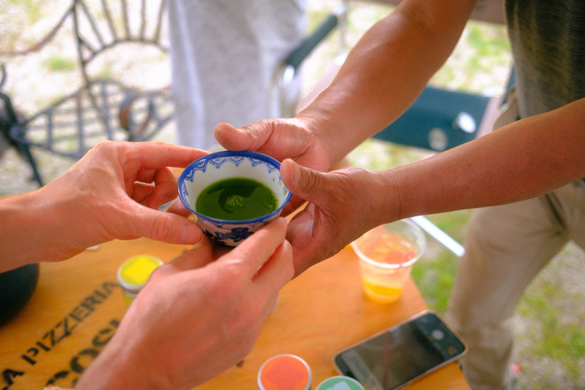 Two people sharing a small bowl of freshly prepared green matcha tea