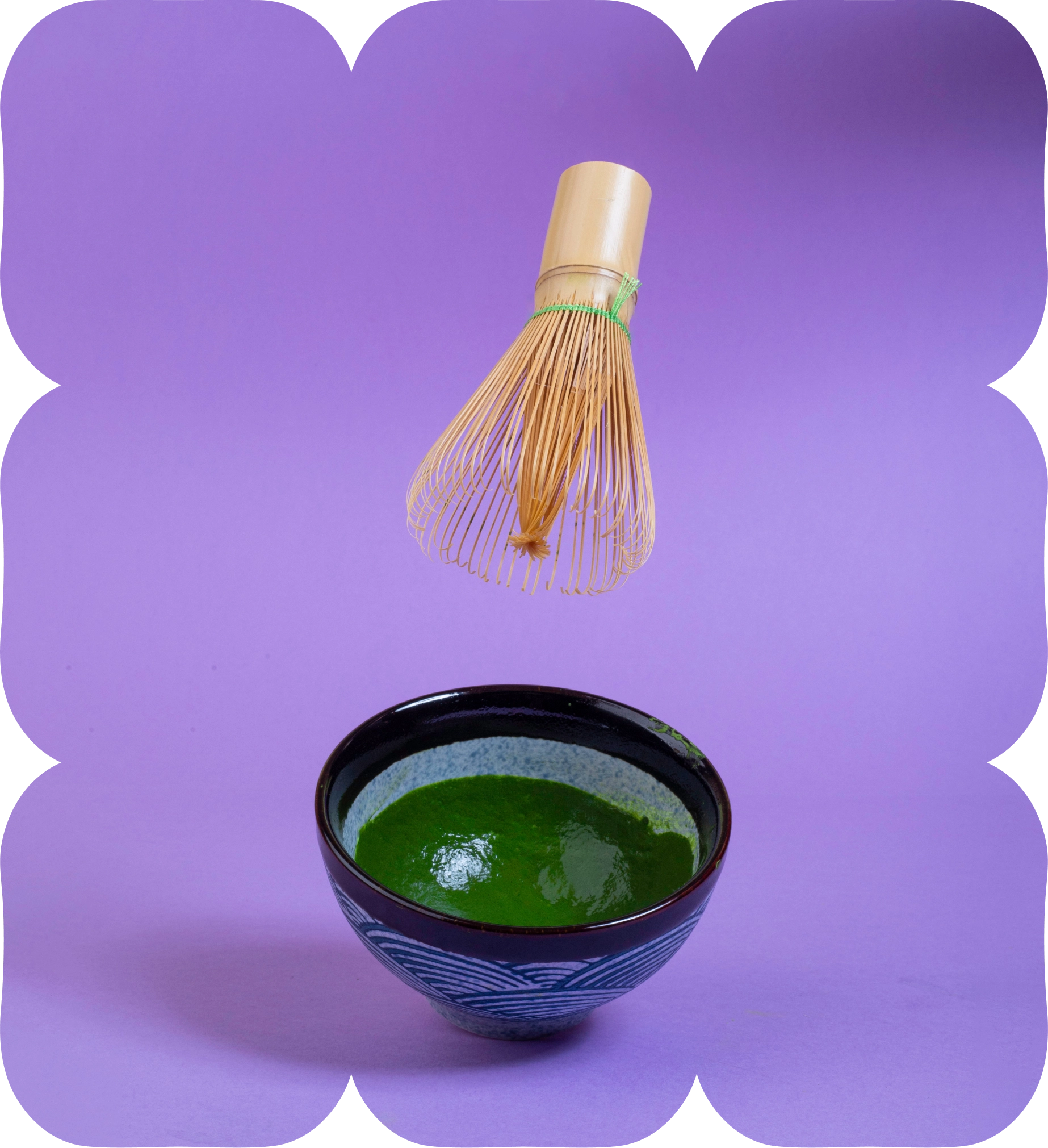 Bamboo matcha whisk above a bowl of freshly prepared green matcha tea