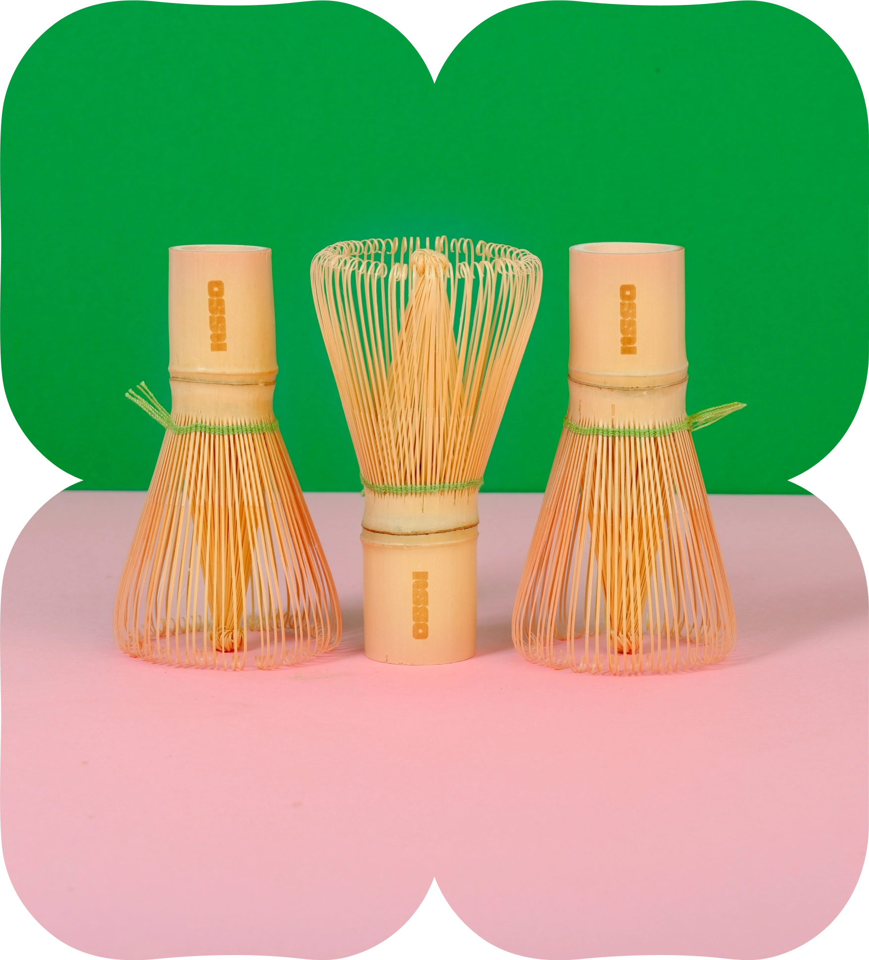 hree bamboo matcha whisks standing upright on a pink and green background