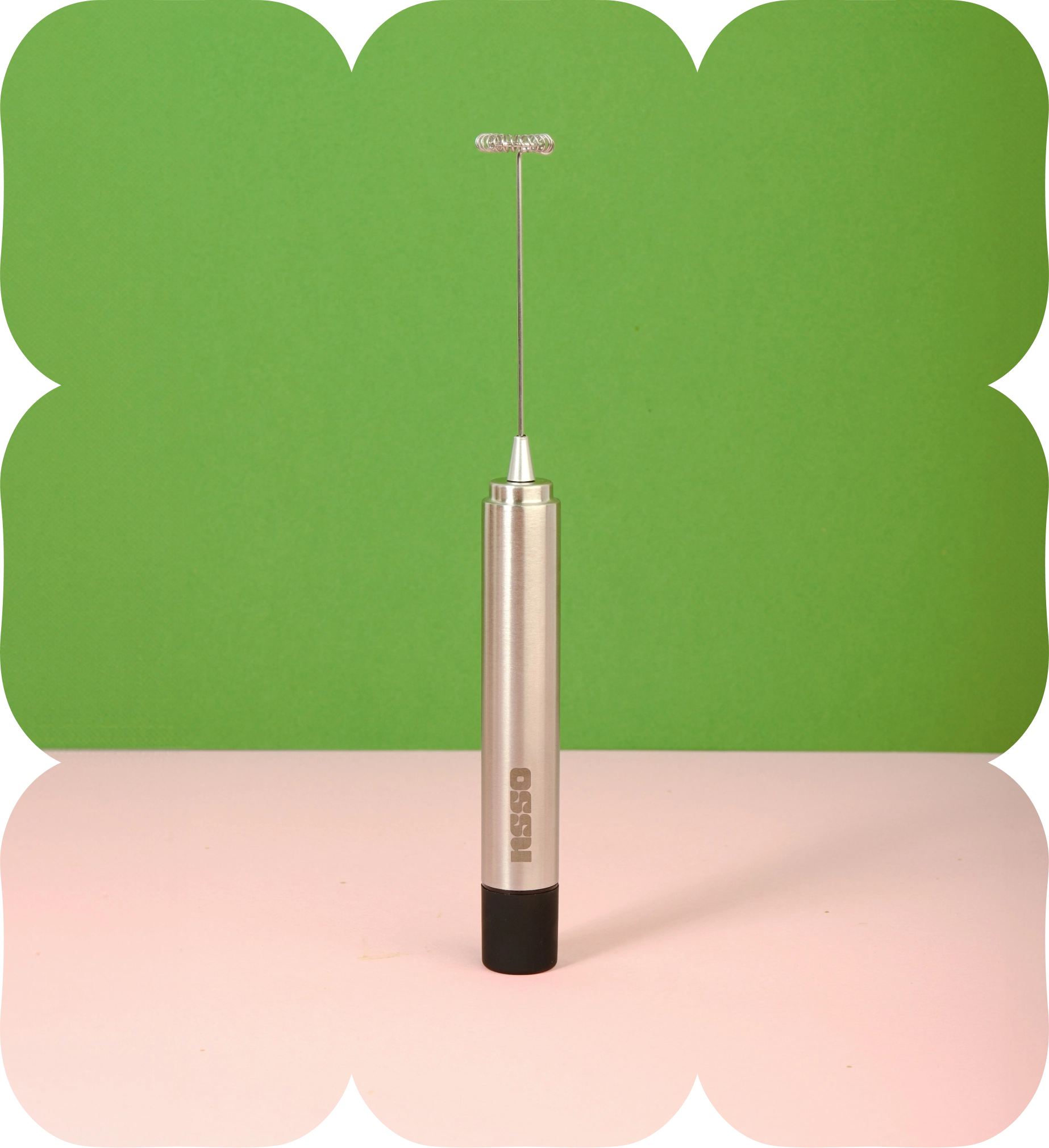 Handheld OSSU electric matcha whisk frother standing upright on a green and pink background