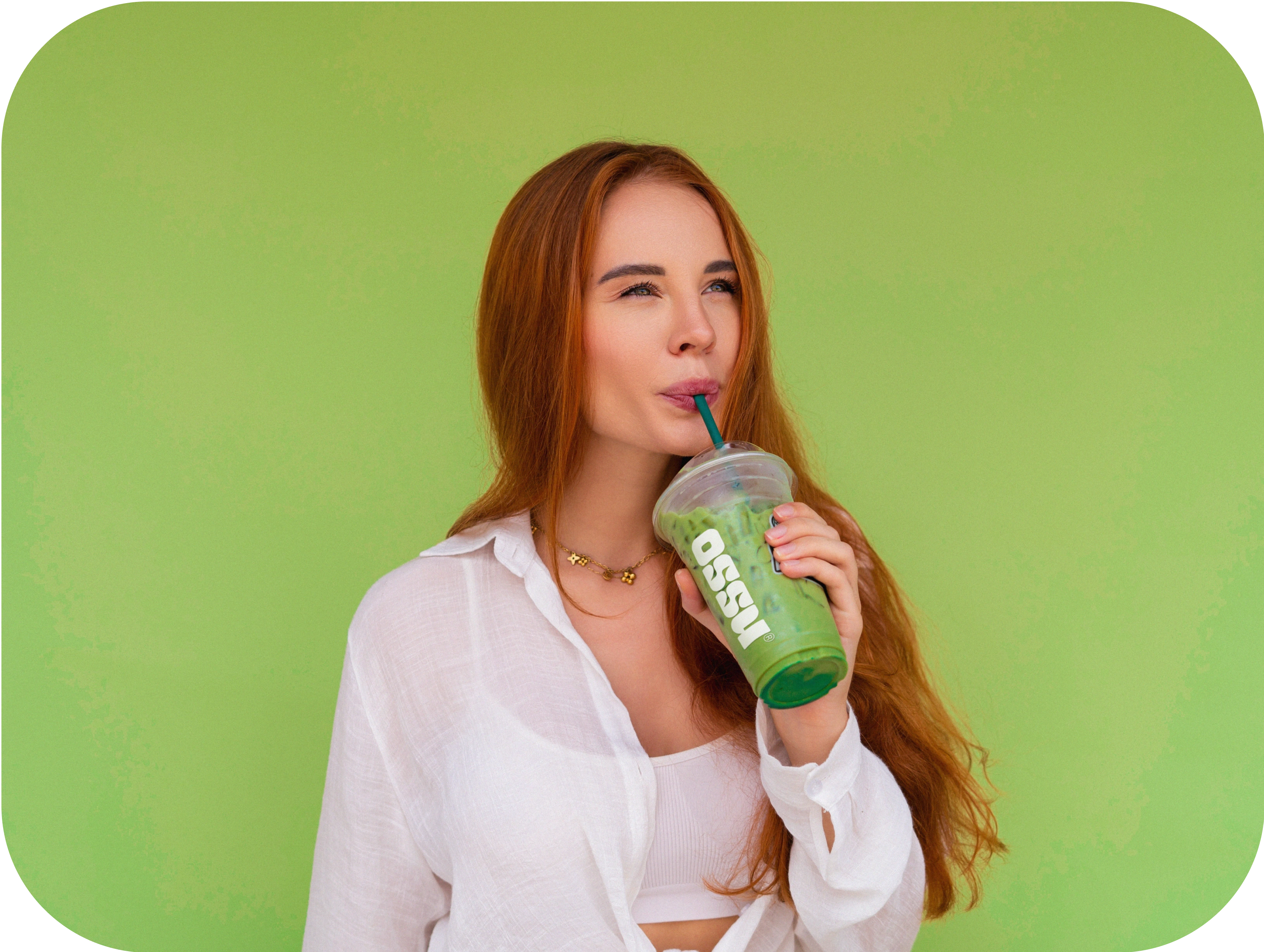 Woman drinking an OSSU iced matcha against a green background