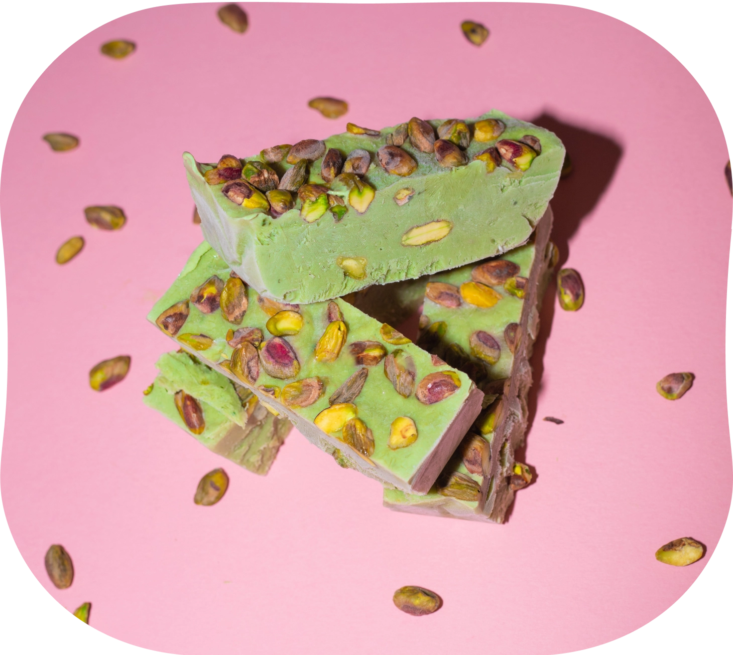 Matcha frozen yoghurt mixture in a parchment-lined tray topped with chopped pistachios