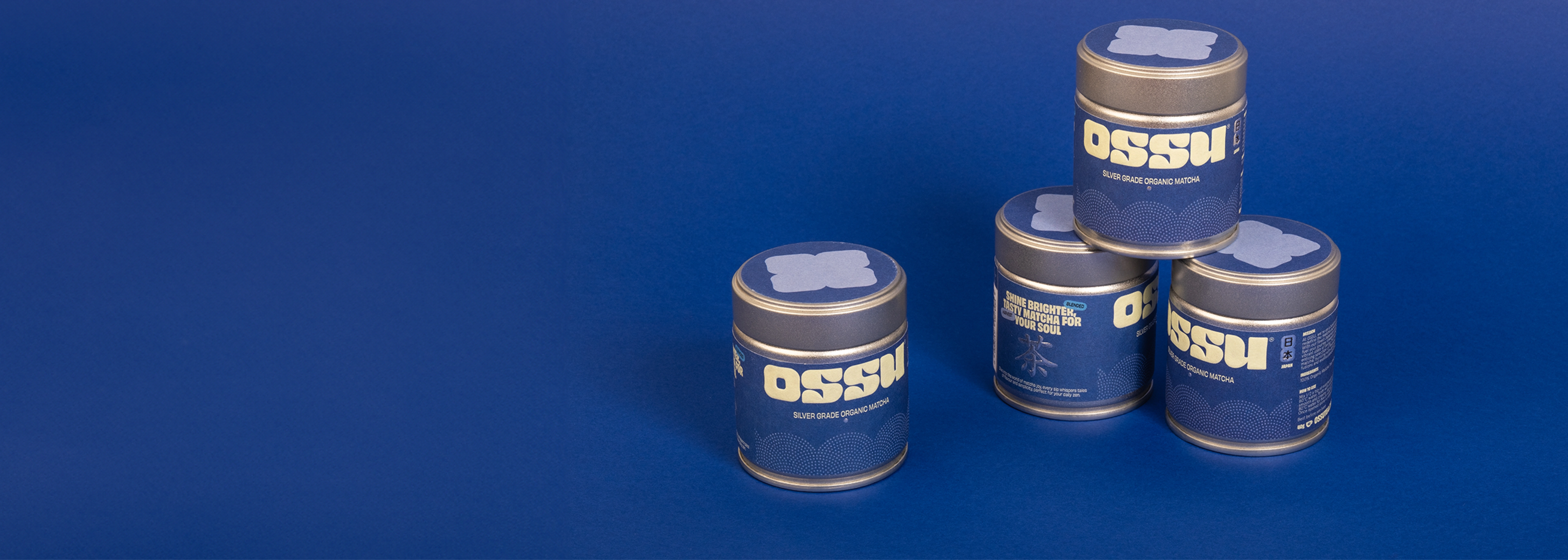 Four OSSU silver grade organic matcha tins stacked against a blue background