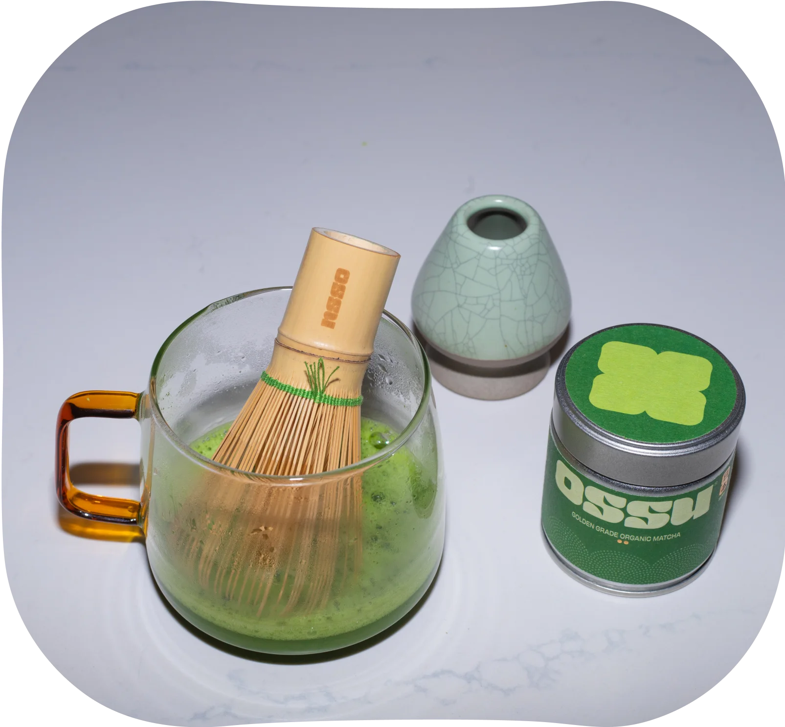 Bamboo whisk stirring matcha in a glass cup to create a light froth