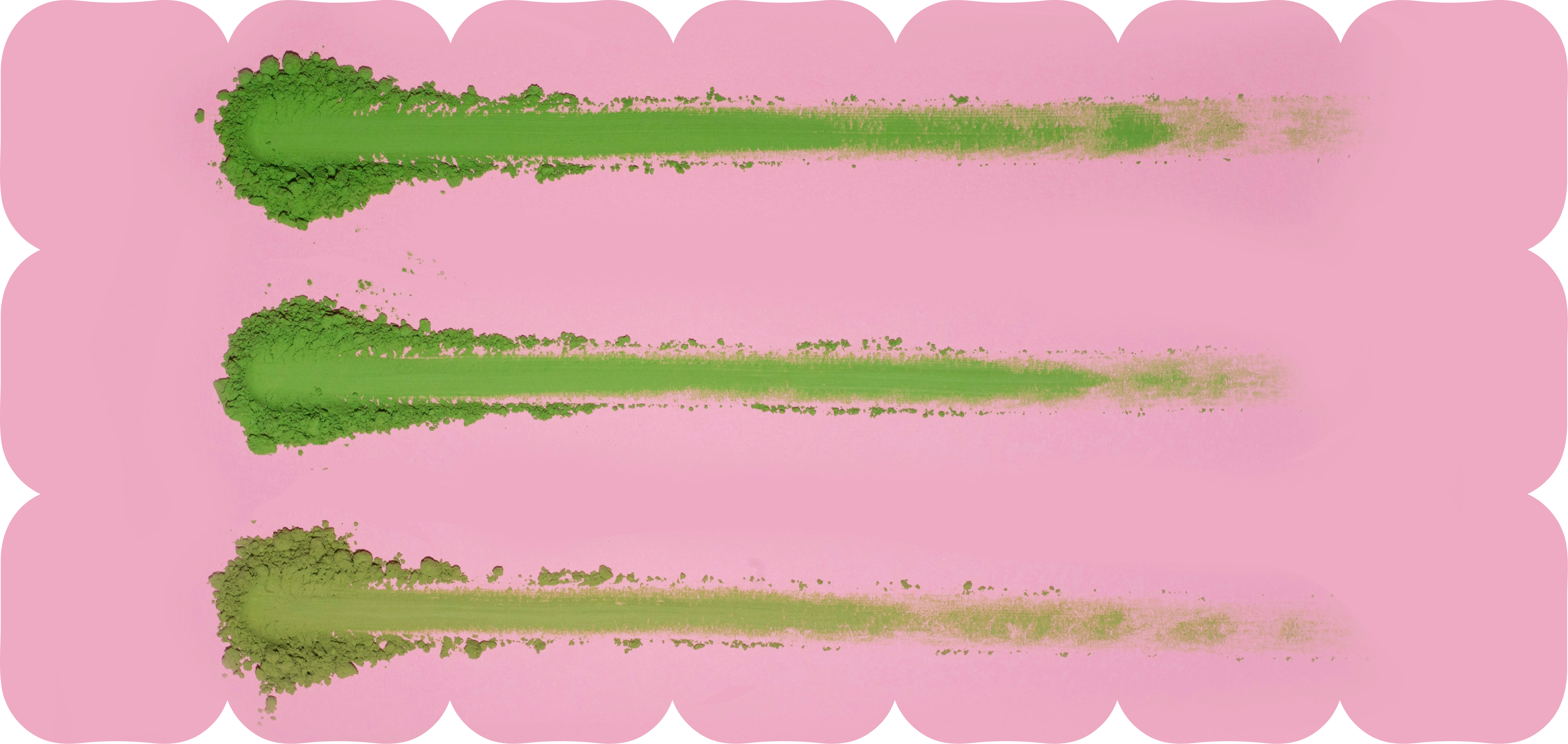 Three streaks of green matcha powder brushed across a pink background