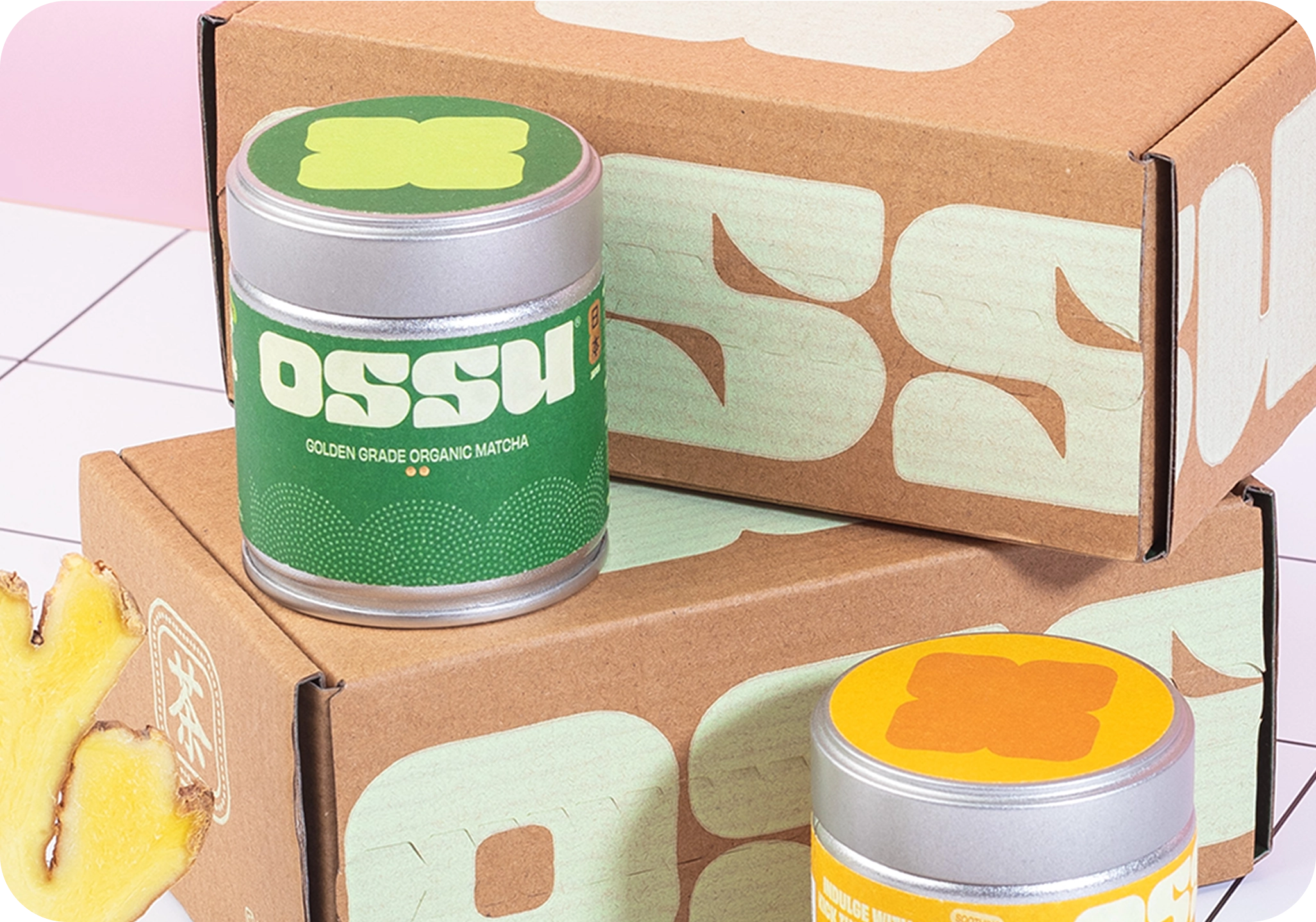 OSSU golden grade organic matcha tin displayed on stacked OSSU boxes with fresh ginger