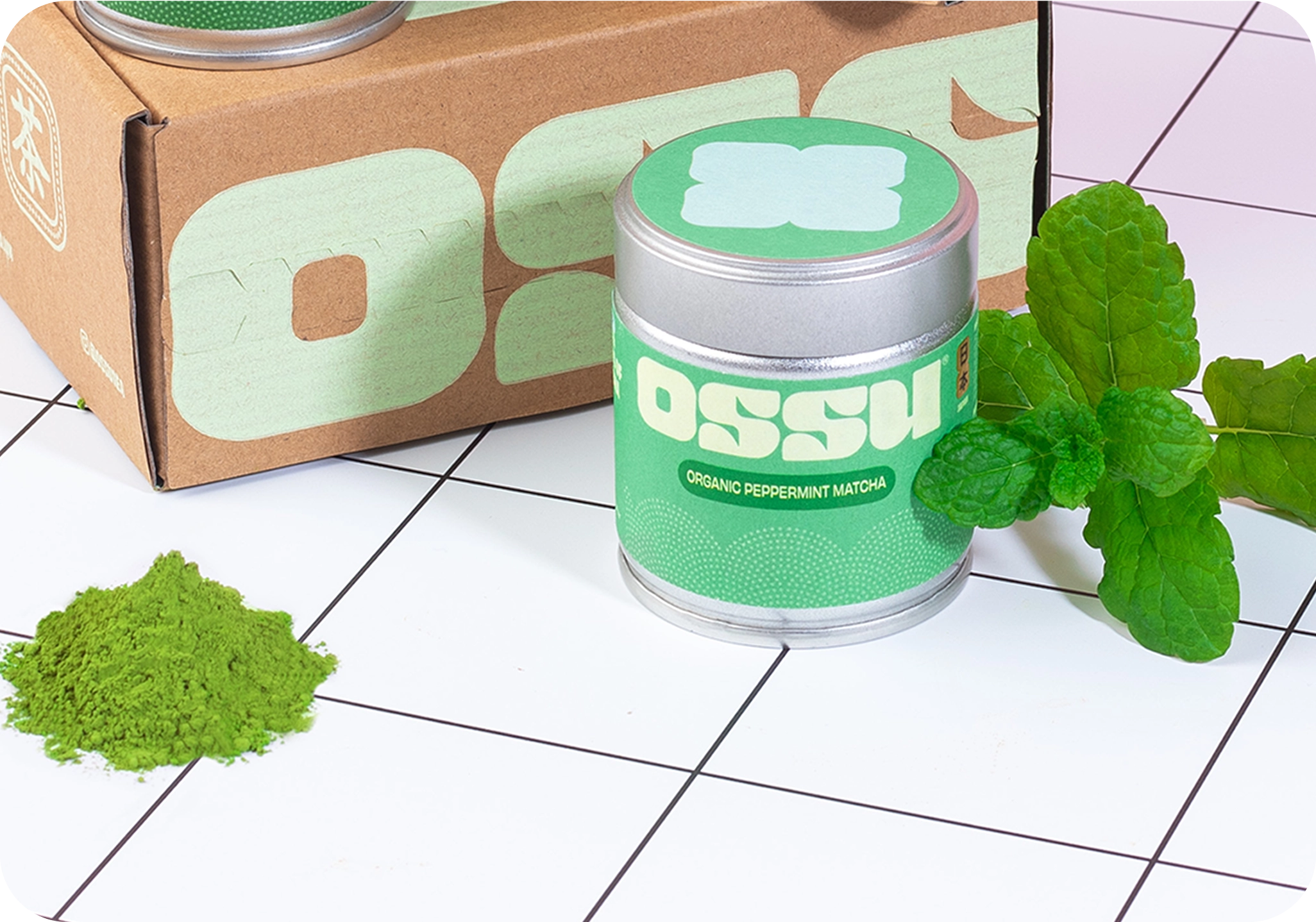 OSSU organic peppermint matcha tin with fresh mint leaves and a pile of matcha powder beside branded OSSU box